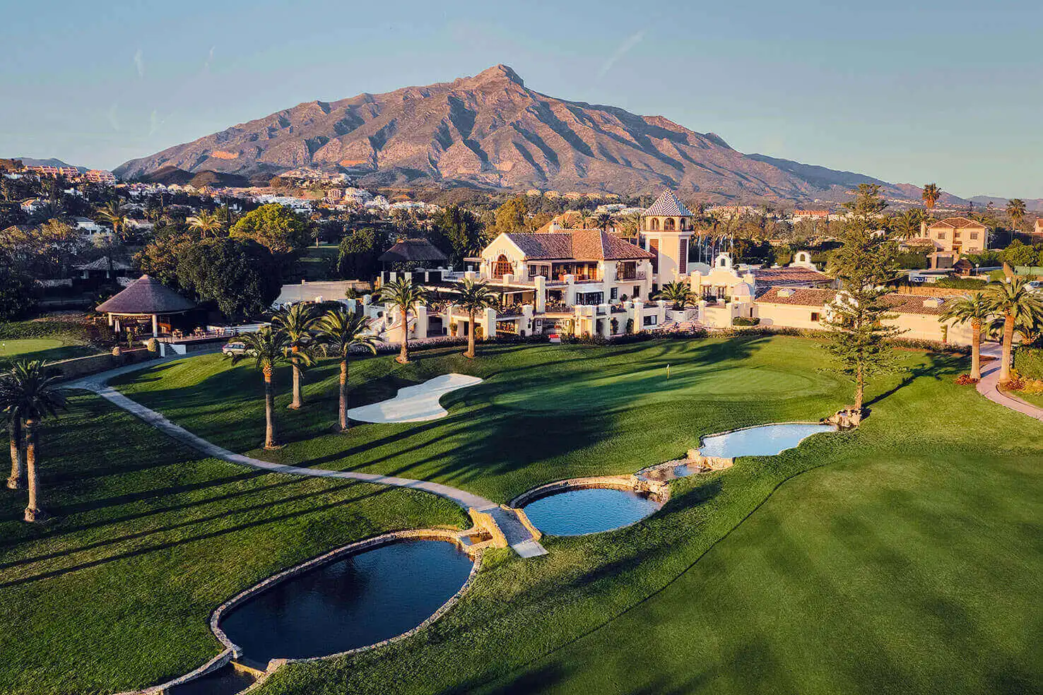 Championship golf course in Marbella with palm-lined fairway and La Concha mountain in the background under a clear blue sky